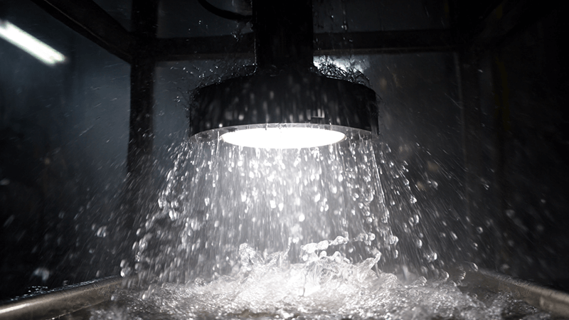 An IP65 rated downlight being tested with a powerful water spray in a lab