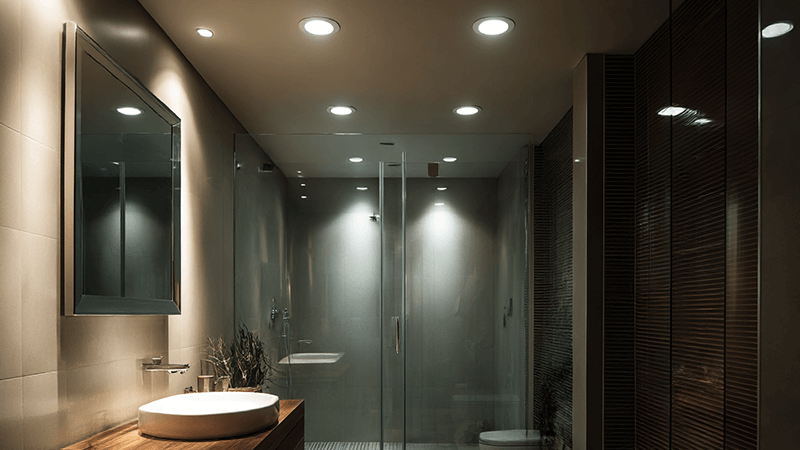 A modern bathroom ceiling with IP65-rated LED downlights installed above the shower area.