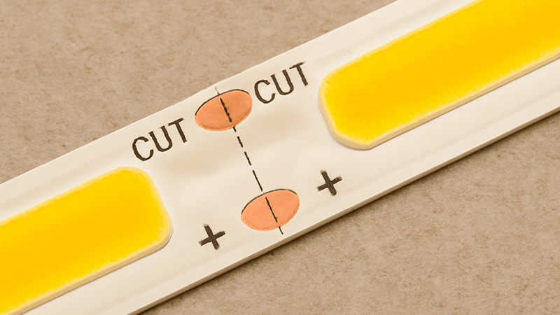 A close-up of a COB LED strip showing the clearly marked copper cut lines.