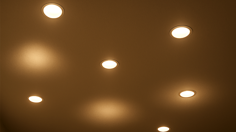 A ceiling with poorly spaced downlights creating pools of light and dark spots