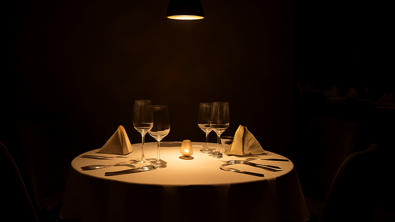 A fine dining restaurant table lit by a single, focused downlight
