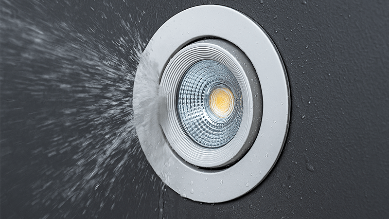 A downlight being tested with water spray to demonstrate its IP rating